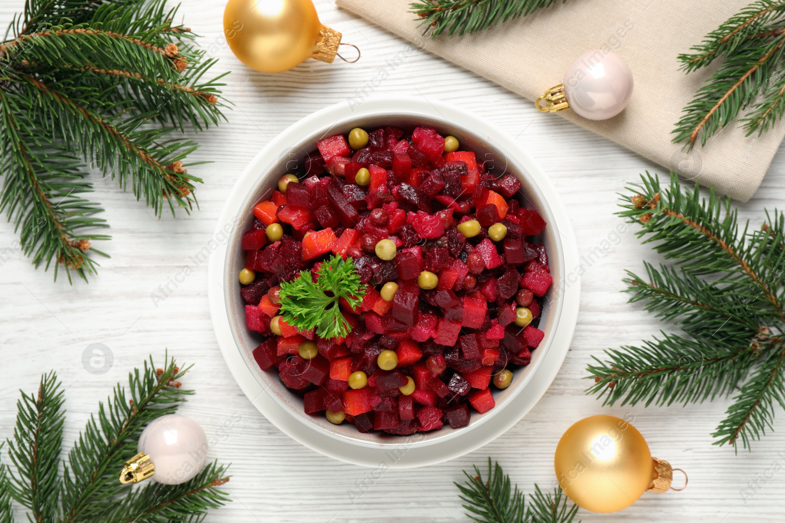 Photo of Traditional Russian salad vinaigrette and Christmas decorations on white wooden table, flat lay