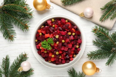 Photo of Traditional Russian salad vinaigrette and Christmas decorations on white wooden table, flat lay