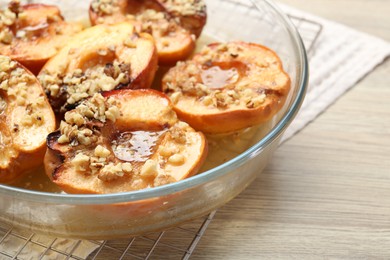 Photo of Delicious baked quinces with nuts and honey in bowl on wooden table, closeup