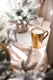 Photo of Golden cupcocoa and Christmas decor on window sill indoors