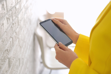Photo of Young woman using modern smartphone indoors, closeup