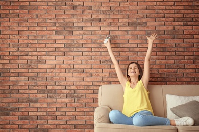 Happy woman with air conditioner remote at home