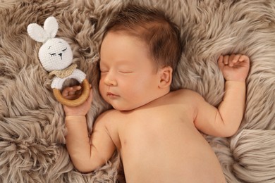 Cute newborn baby sleeping with toy on fluffy blanket, top view