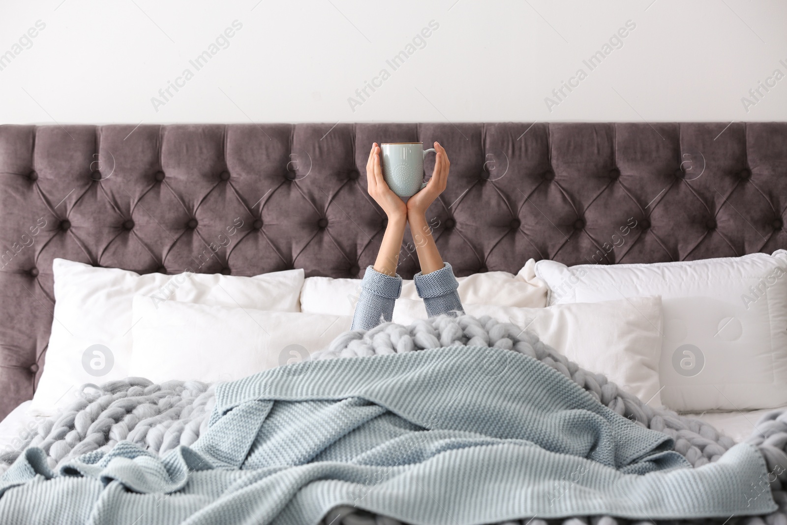 Photo of Woman with cup of coffee on bed at home