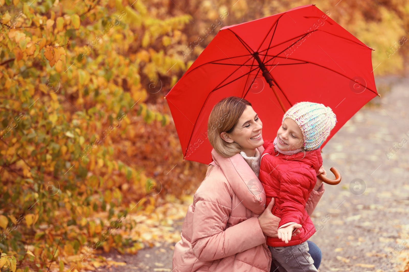 Photo of Mother and daughter with umbrella in autumn park on rainy day