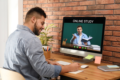Image of Young man using computer for online studying at home