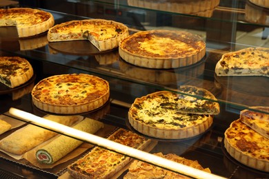 Photo of Different delicious quiches on counter in bakery shop