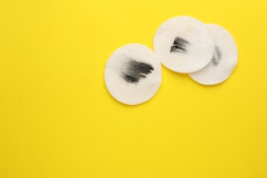 Photo of Dirty cotton pads after removing makeup on yellow background, flat lay. Space for text