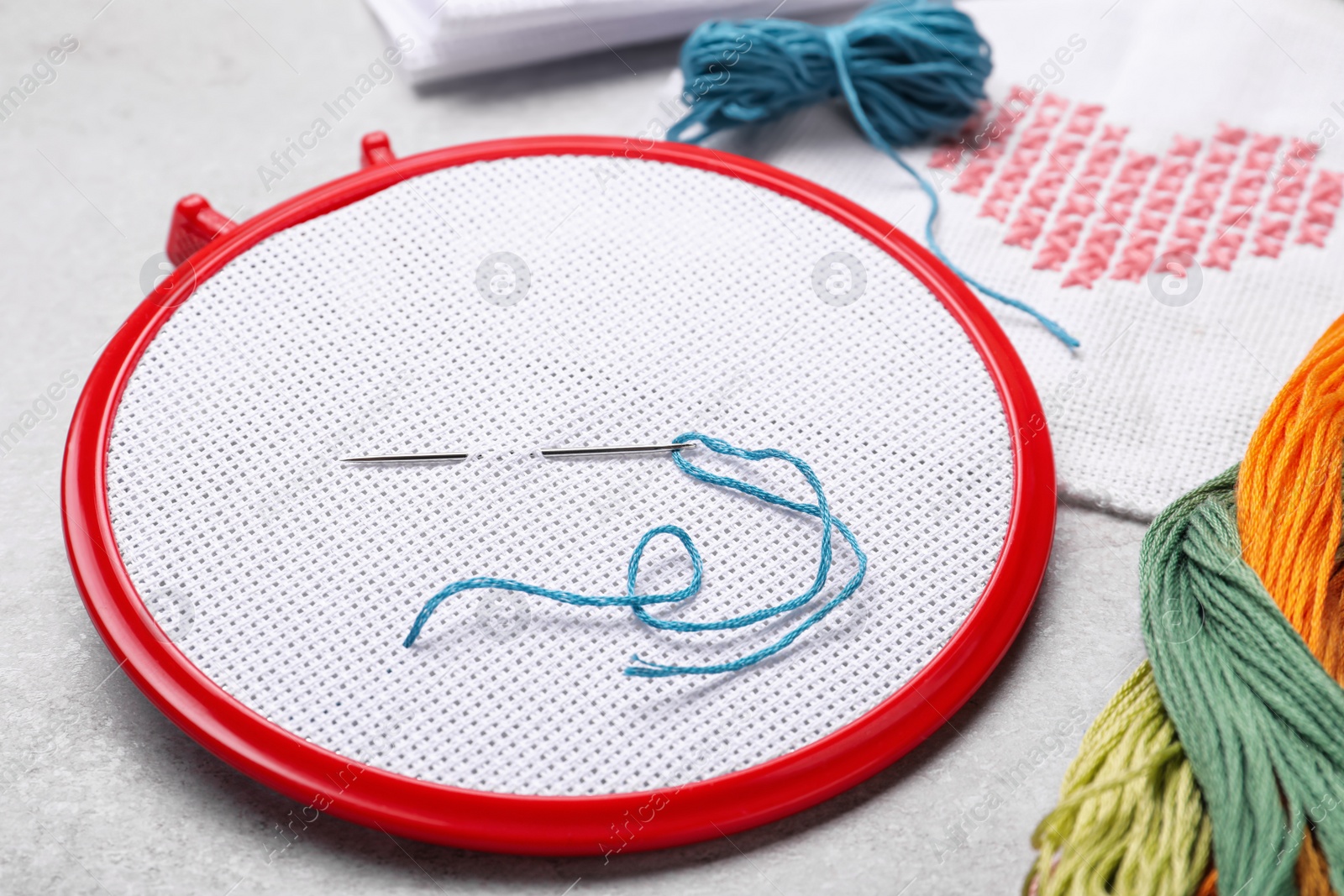 Photo of Embroidery hoop with fabric and needle on white table, closeup