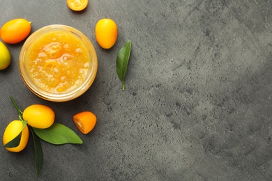 Delicious kumquat jam and fresh fruits on grey table, flat lay. Space for text