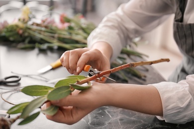 Photo of Female florist pruning stem over table, closeup