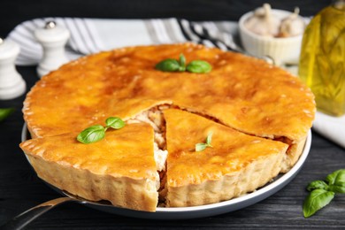 Delicious meat pie with basil on black table, closeup