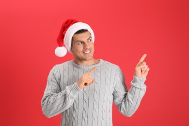 Photo of Handsome man wearing Santa hat on red background