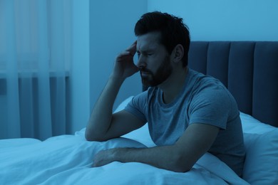 Photo of Man suffering from headache in bed at night