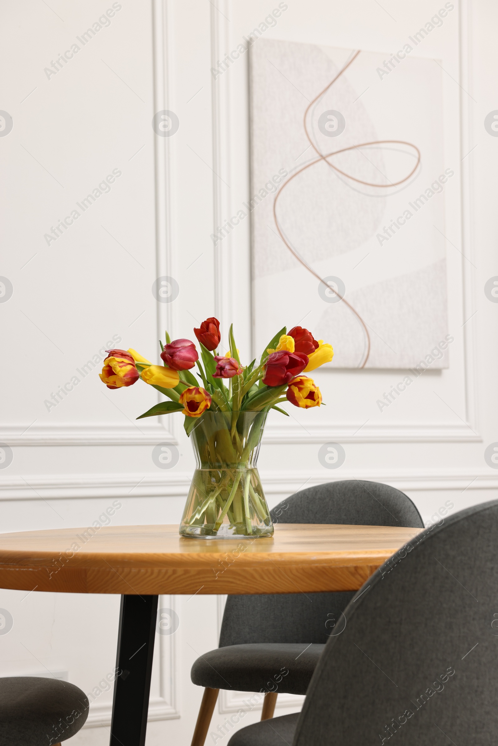 Photo of Vase with beautiful tulips on table in dining room