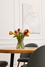 Photo of Vase with beautiful tulips on table in dining room