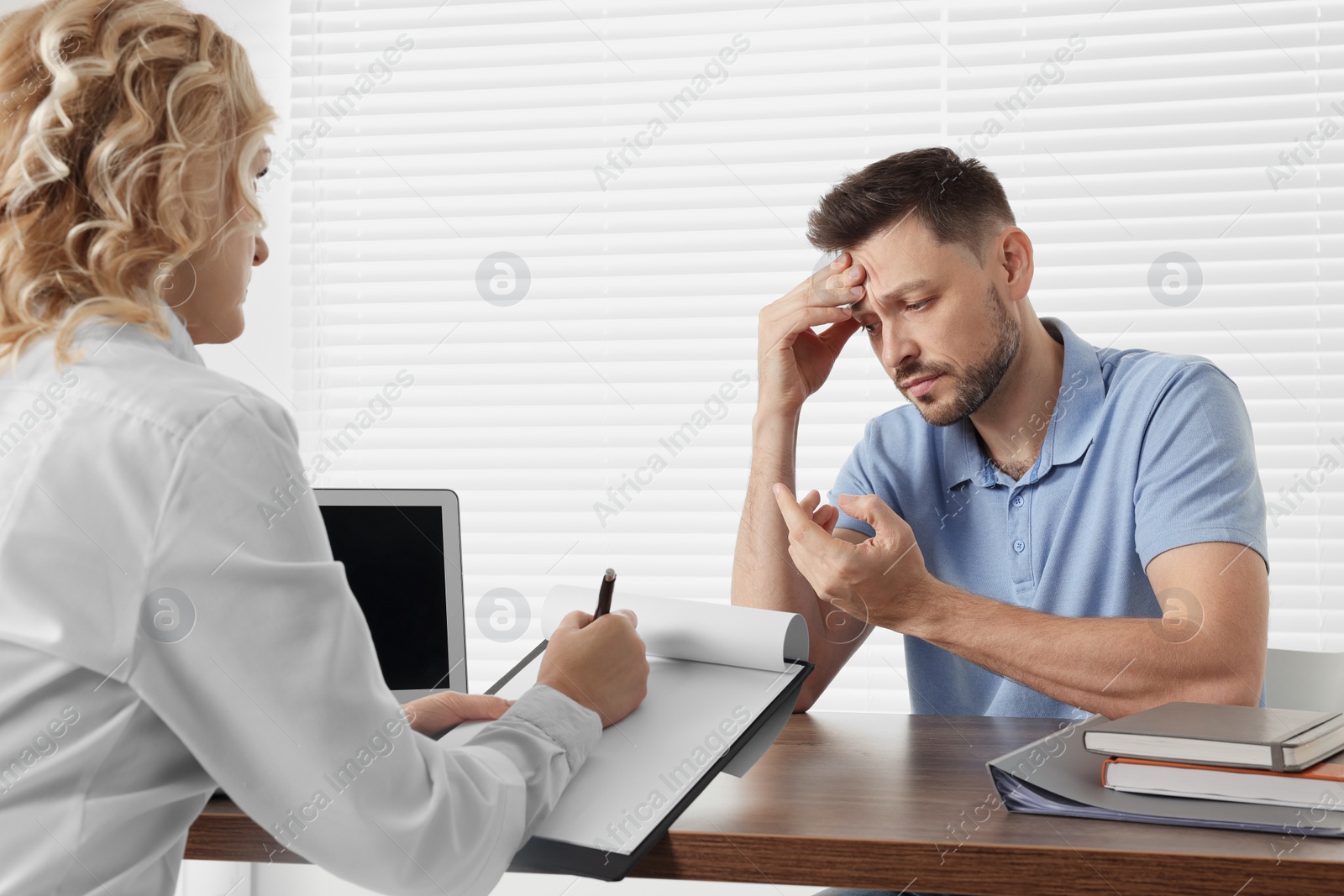 Photo of Doctor consulting patient at table in clinic