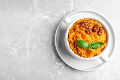 Photo of Bowl of tasty sweet potato puree on grey marble table, top view. Space for text