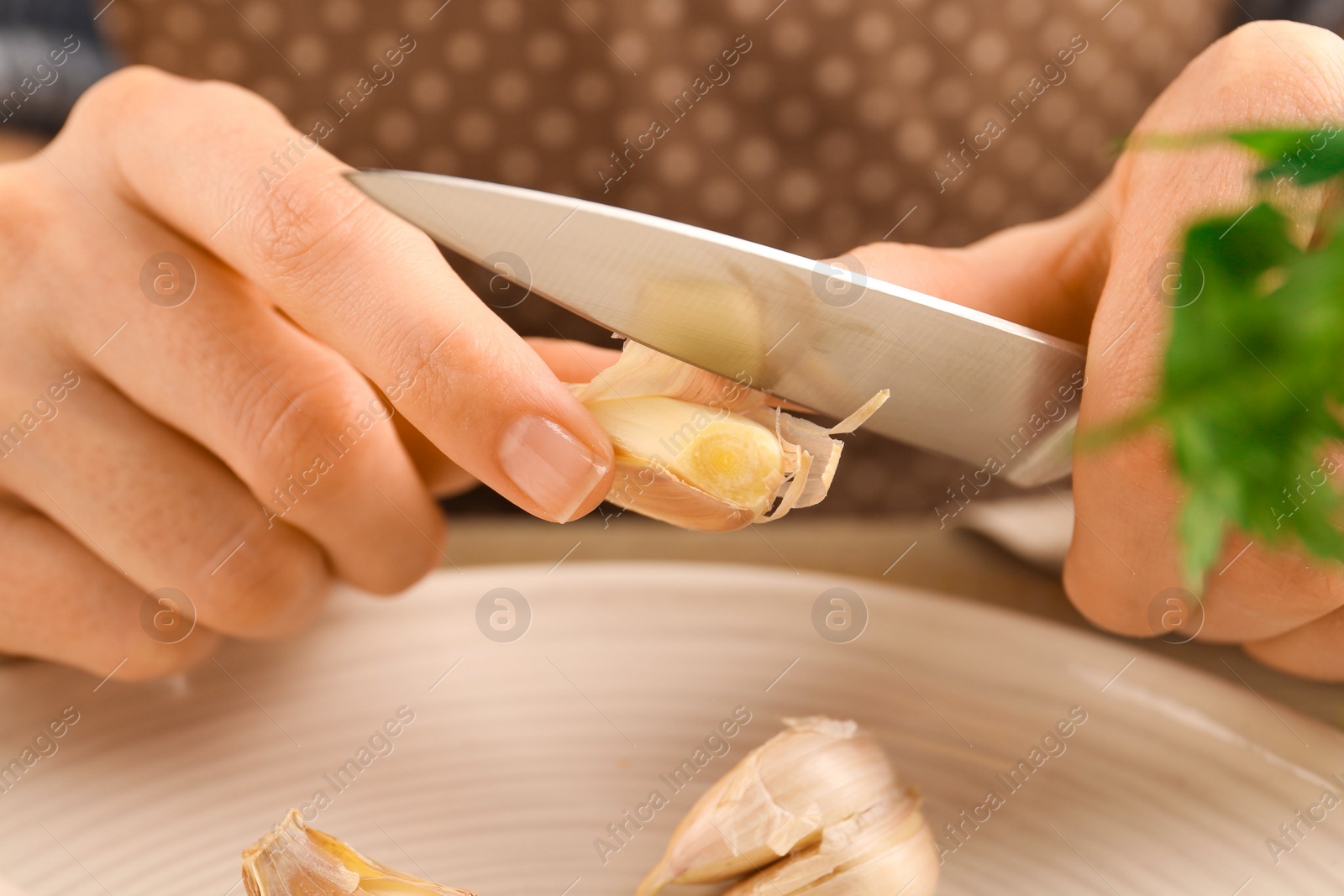 Photo of Woman peeling fresh garlic at table, closeup