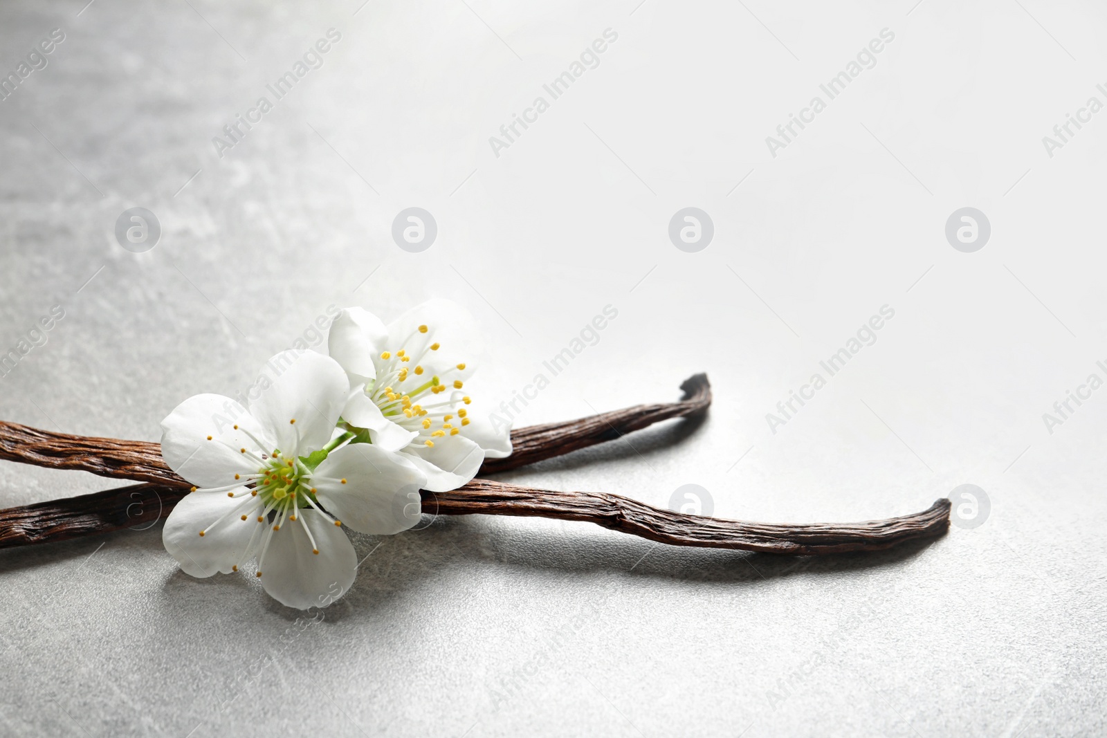 Photo of Vanilla sticks and flowers on grey background