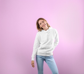 Portrait of woman in hoodie sweater on color background. Space for design