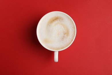 Photo of Tasty cappuccino in coffee cup on red background, top view
