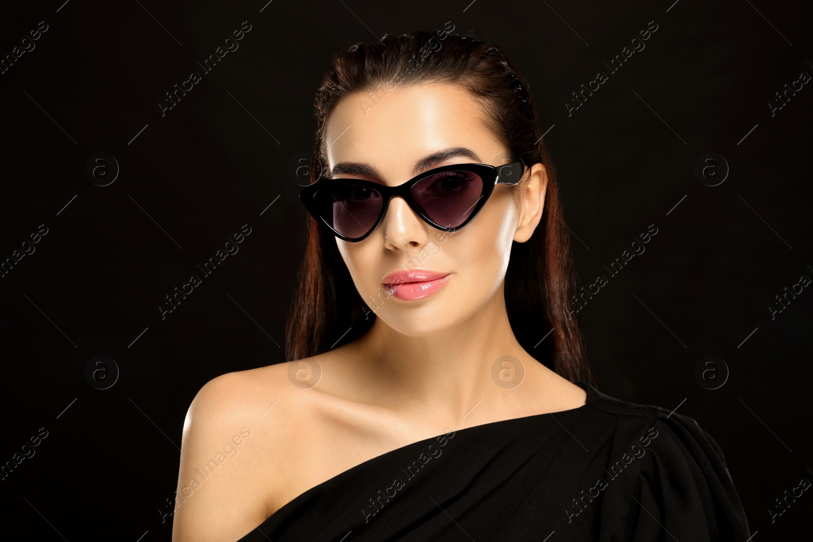 Photo of Portrait of beautiful young woman in stylish sunglasses on black background