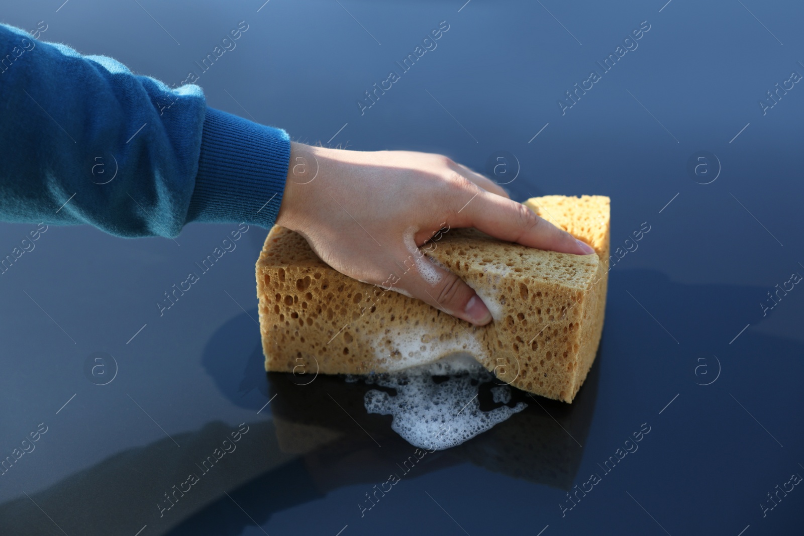 Photo of Man washing car hood with sponge, closeup