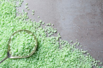 Photo of Spoon with light green sea salt on grey table, flat lay. Space for text