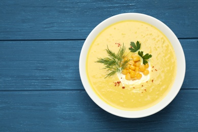 Photo of Delicious creamy corn soup served on blue wooden table, top view. Space for text