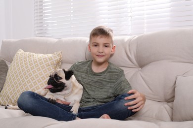 Photo of Boy with his cute pug on sofa at home