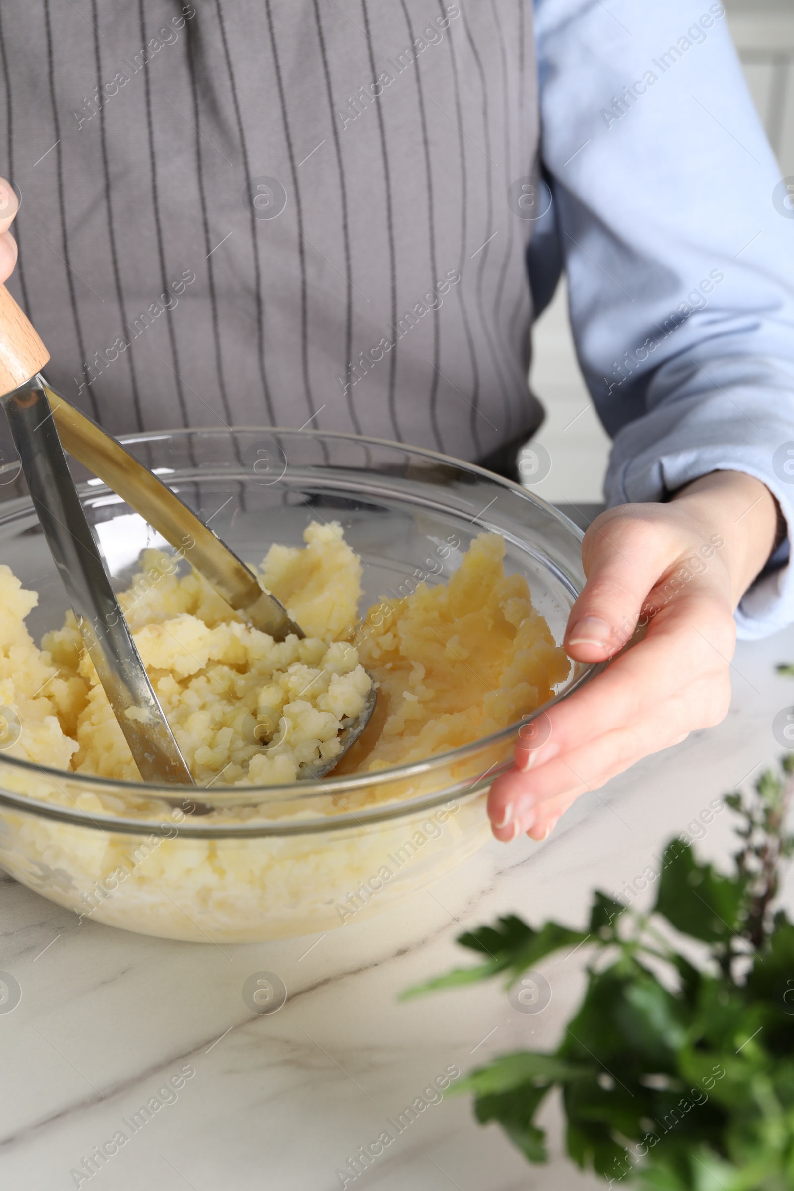 Photo of Woman making mashed potato at white marble table, closeup