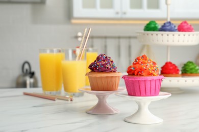 Delicious cupcakes with colorful cream and sprinkles on white table