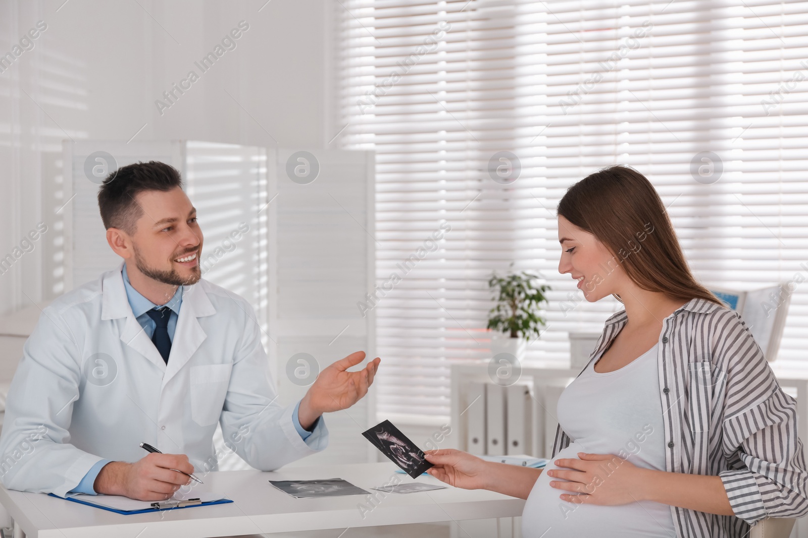 Photo of Pregnant woman with ultrasound picture at doctor's appointment in clinic