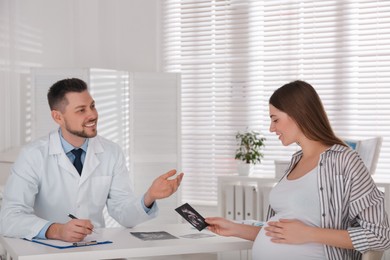 Pregnant woman with ultrasound picture at doctor's appointment in clinic