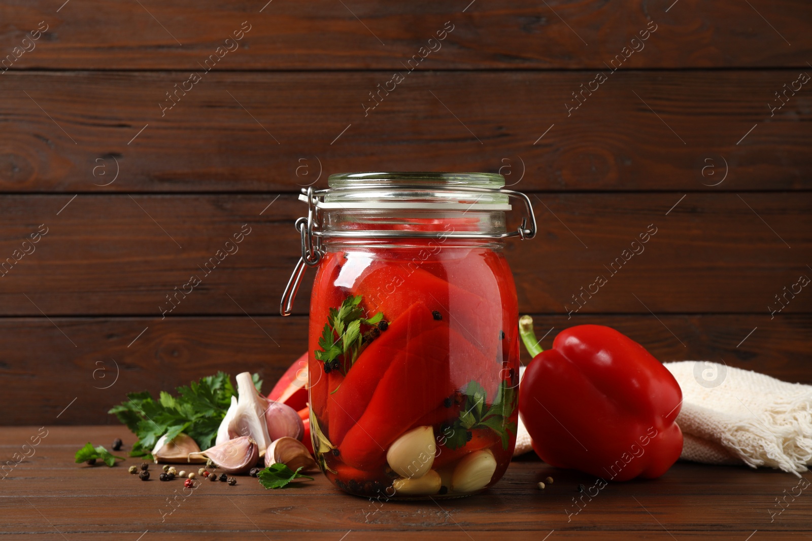 Photo of Glass jar with pickled peppers on wooden table