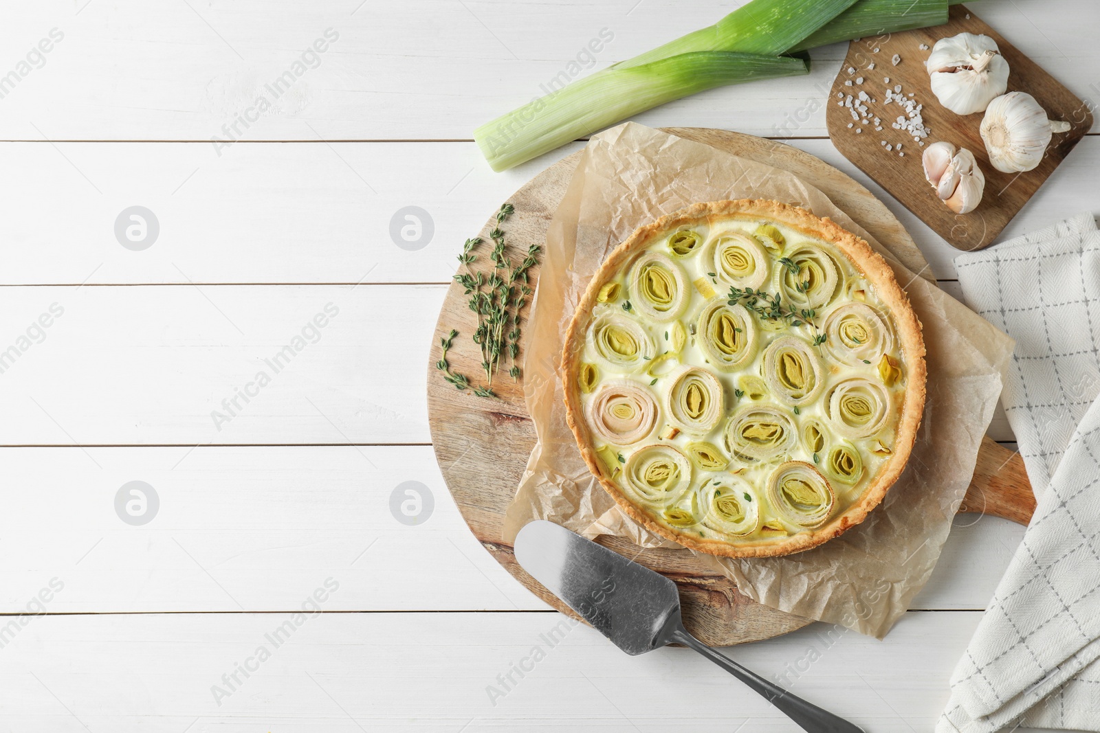 Photo of Flat lay composition with tasty leek pie and products on white wooden table. Space for text
