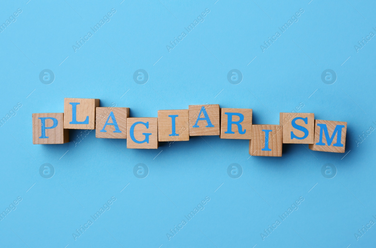 Photo of Word Plagiarism made of wooden cubes with letters on light blue background, top view