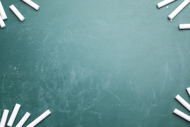 Photo of Pieces of white chalk on greenboard, flat lay. Space for text