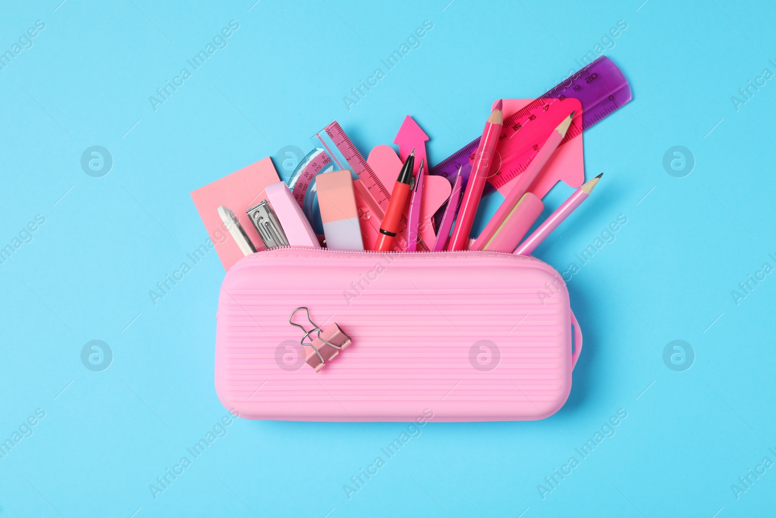 Photo of Pencil case with different stationery on light blue background, top view. Back to school