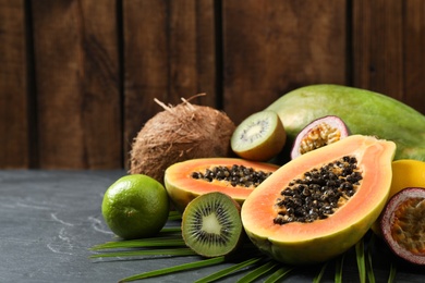 Photo of Fresh ripe papaya and other fruits on black table. Space for text