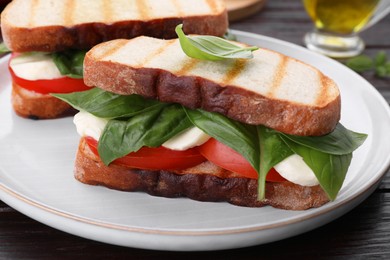 Delicious Caprese sandwiches with mozzarella, tomatoes and basil on wooden table, closeup