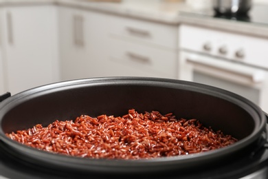 Photo of Modern multi cooker with boiled brown rice in kitchen, closeup. Space for text