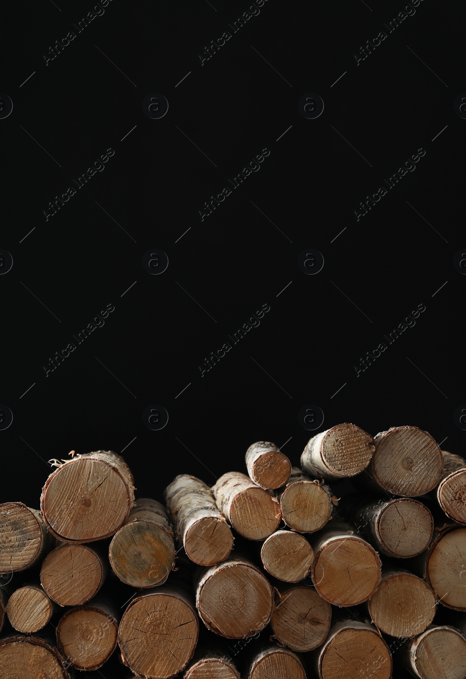 Photo of Cut firewood on black background. Space for text