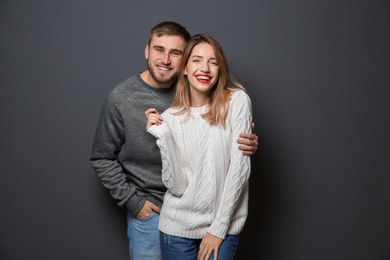 Photo of Young couple in warm sweaters on dark background