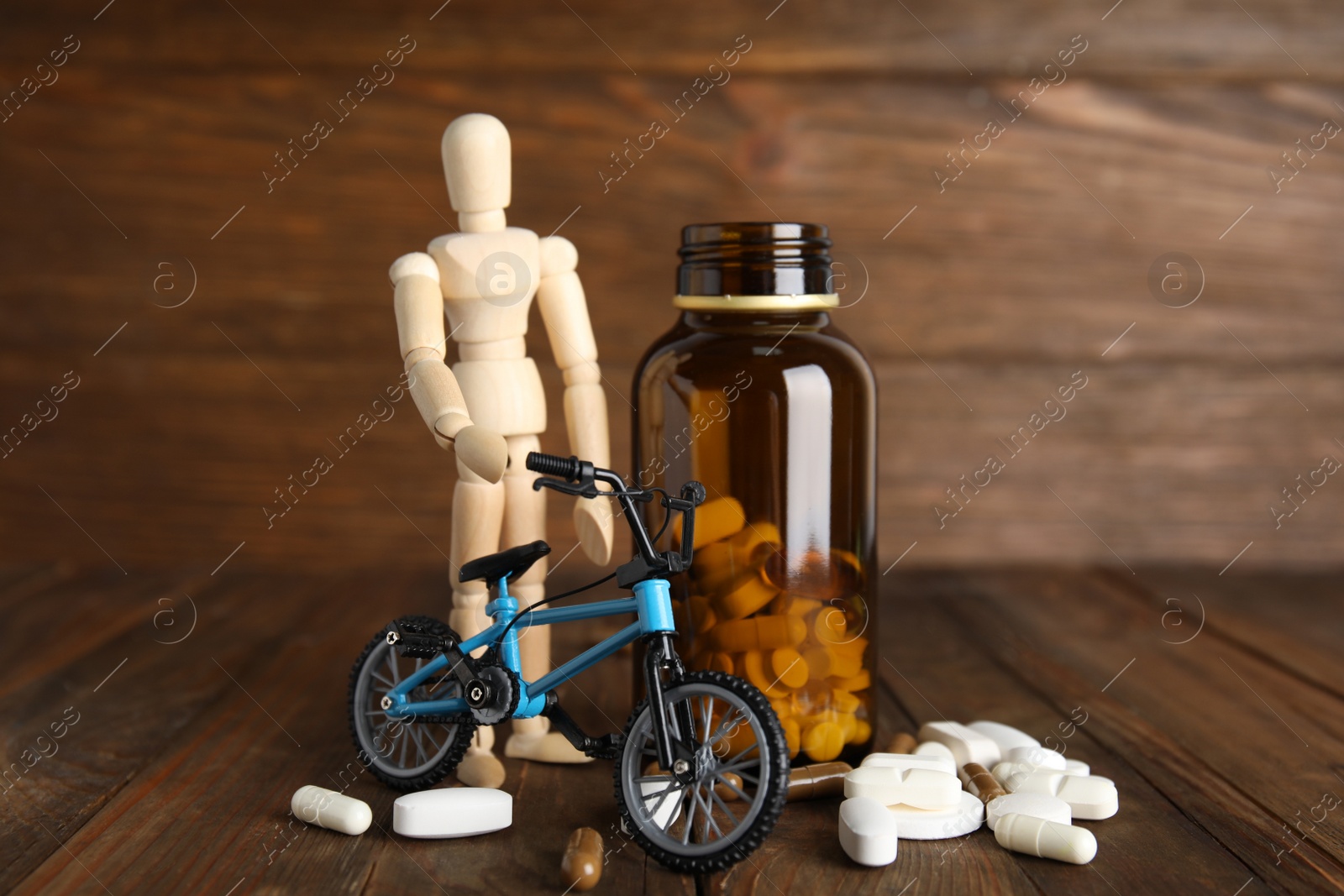 Photo of Pills, sportsman and bike model on wooden background. Using doping in cycling sport concept