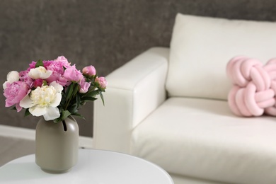 Photo of Vase with bouquet of beautiful peonies on table in room, space for text