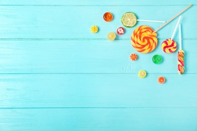 Photo of Flat lay composition with different candies and space for text on color wooden background