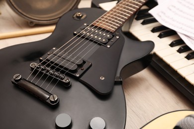 Photo of Modern electric guitar near other musical instruments on wooden background, closeup