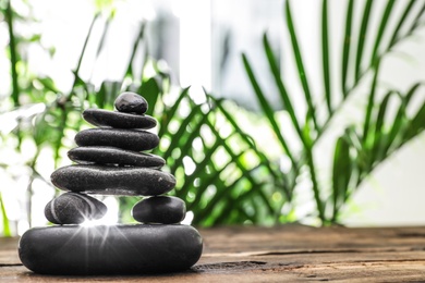 Photo of Table with stack of stones and blurred green leaves on background, space for text. Zen concept